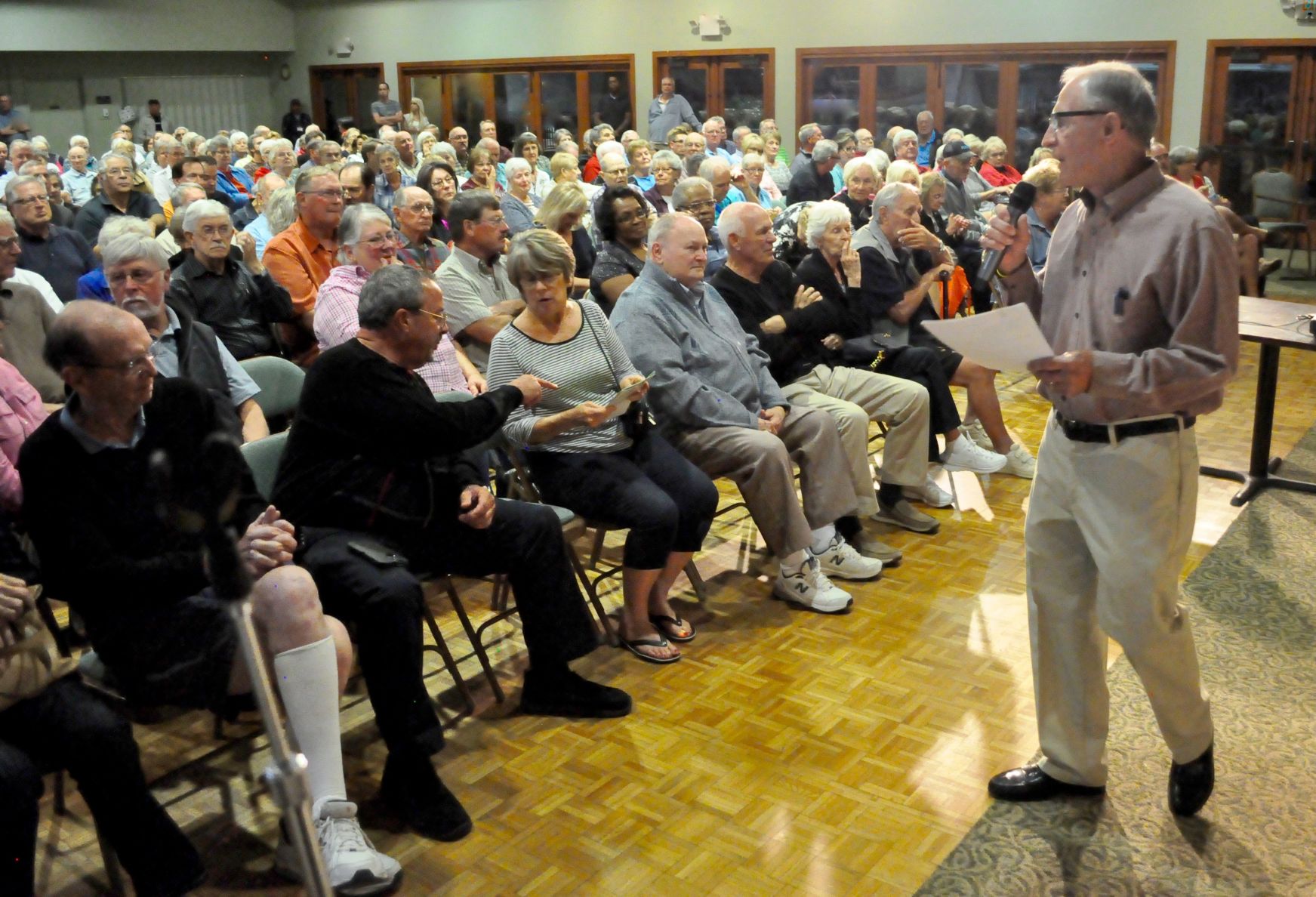 Host Ben Holt speaks to the crowd at the beginning of a Golf Course Town Hall meeting